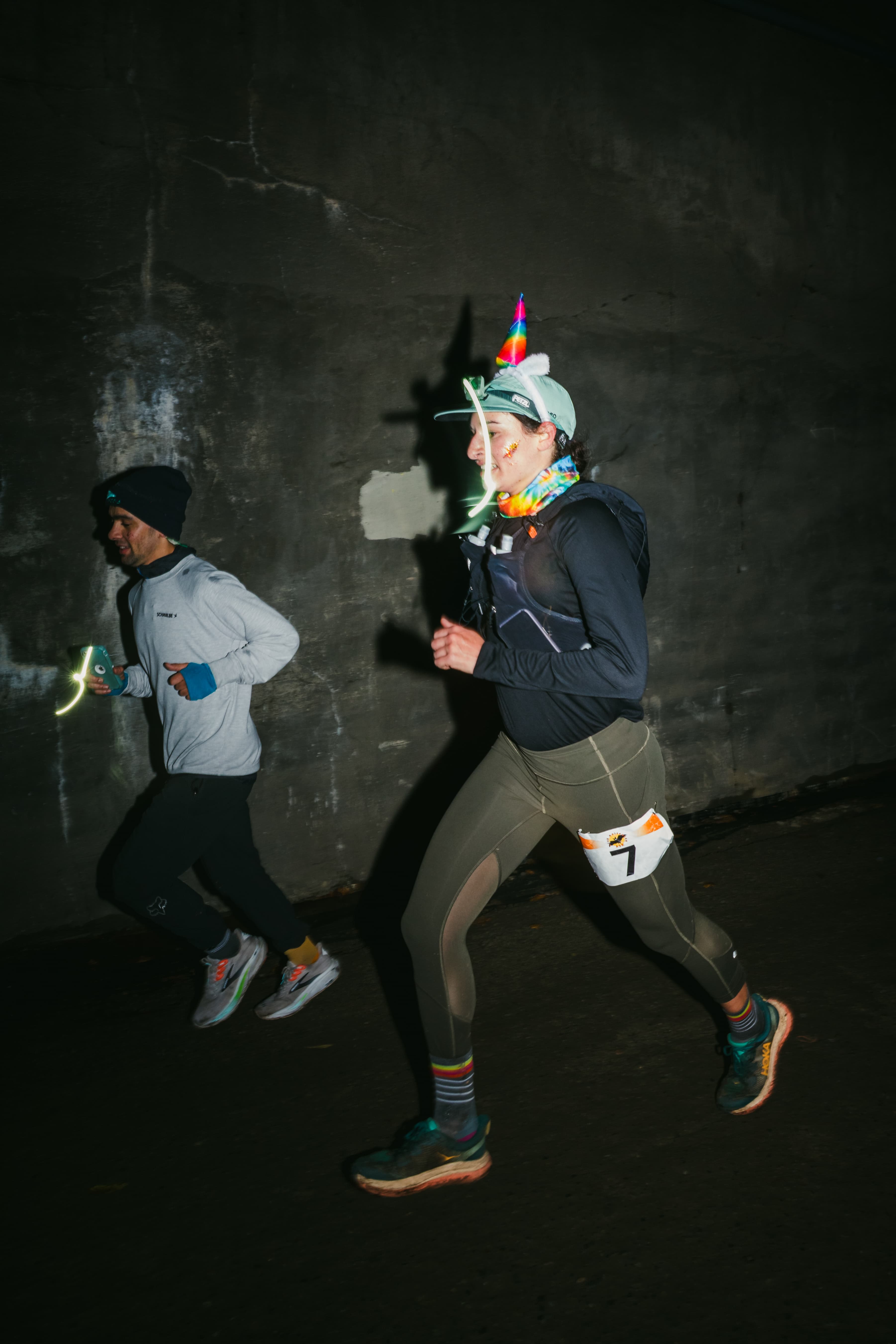Headlamp-lit Hyak Passage runners moving through the dark Snoqualmie Tunnel