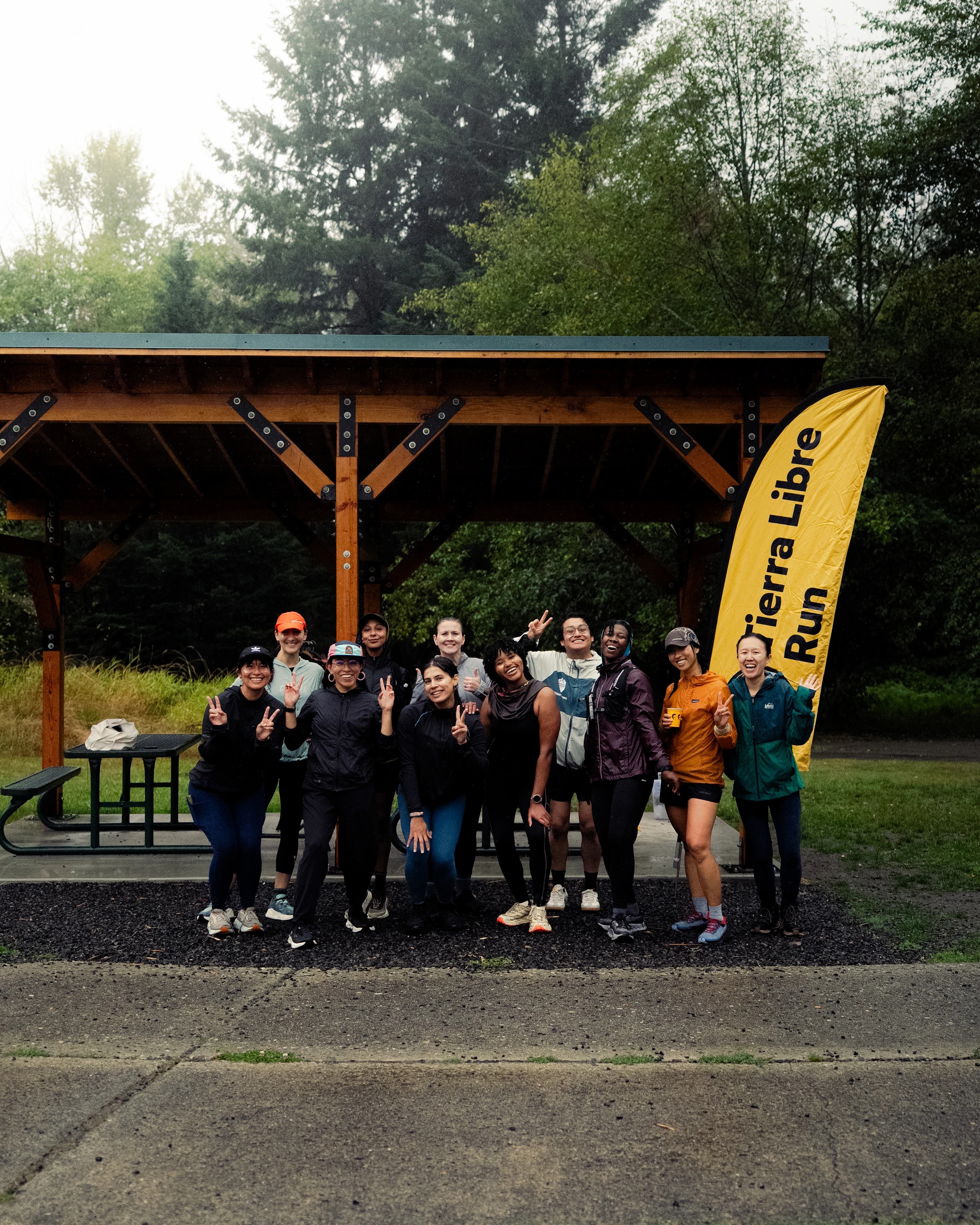 Tierra Libre runners together beside their yellow flag at a community gathering