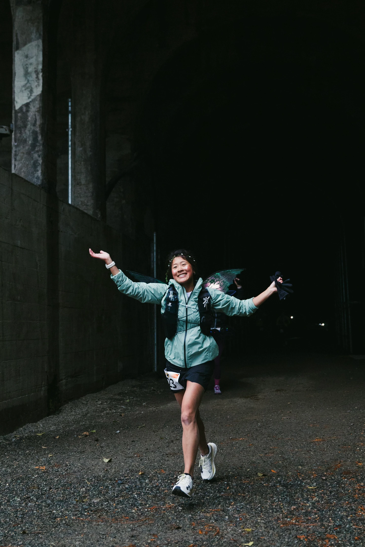 A smiling Hyak Passage runner celebrating with her arms outstretched